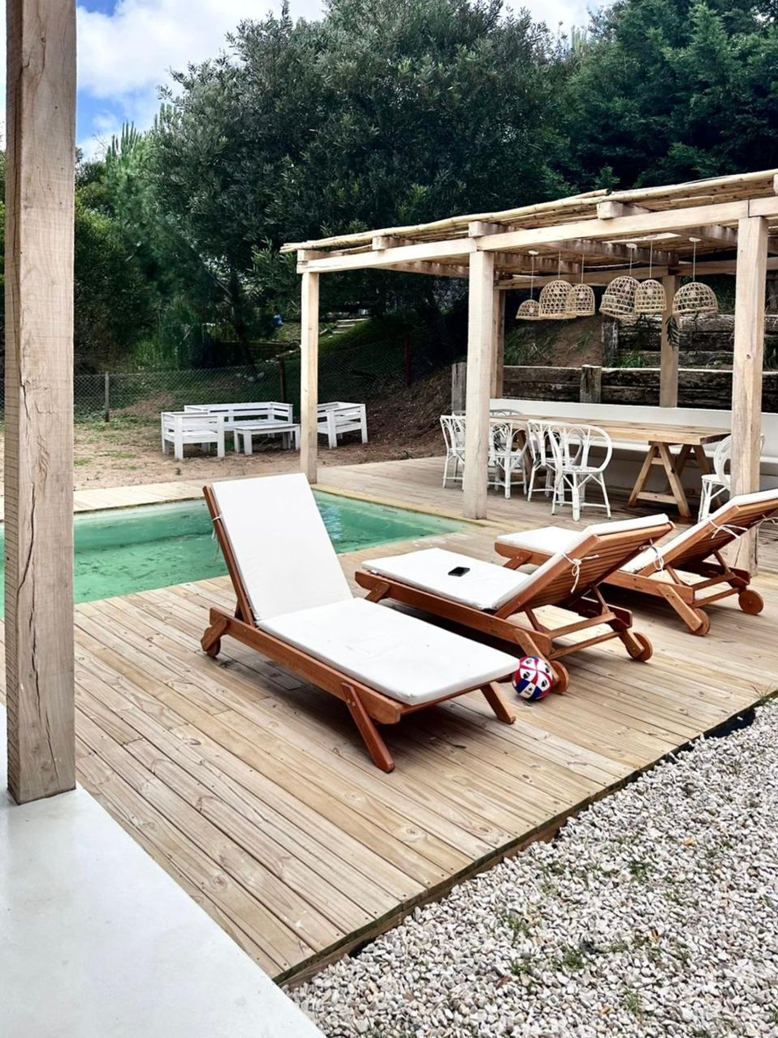 Area de piscina rústica con pérgola de madera y deck — proyecto CE, por arquitectura.JD, en Pinamar